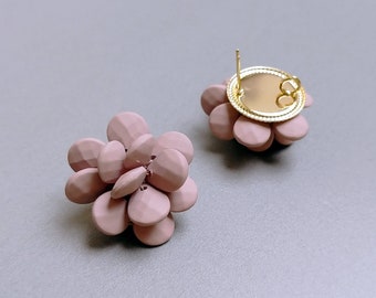 May include: A pair of pink flower-shaped earrings. The earrings are made of small, round, textured pieces of plastic. The earrings have a gold-colored post and back.