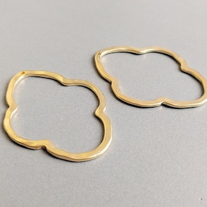 Puede incluir: Dos pendientes de metal de color dorado con forma de trébol de cuatro hojas.
