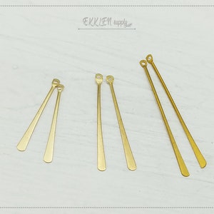 May include: Five gold-colored metal earring hooks with a loop at the top. The hooks are straight and have a slightly rounded end.
