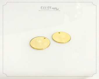 May include: Two gold-colored metal circles with a small hole in the center. The circles are smooth and shiny.
