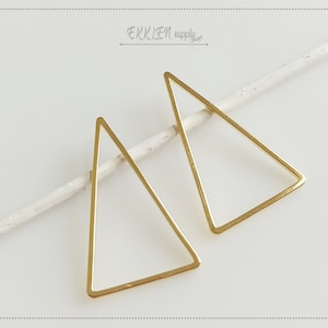 May include: Two gold triangle shaped metal hoops. The hoops are open on one side and are designed to be used for jewelry making.