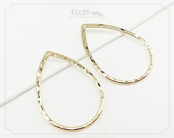May include: Two gold-toned teardrop-shaped metal earring blanks with a hammered texture.