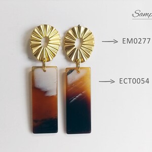 Puede incluir: Un par de pendientes de declaraci&oacute;n dorados y marrones con un dise&ntilde;o geom&eacute;trico. Los pendientes presentan una parte superior redonda de oro texturizado y una parte inferior rectangular marr&oacute;n con un patr&oacute;n de m&aacute;rmol blanco y marr&oacute;n. Los pendientes est&aacute;n etiquetados como EM0277 y ECT0054.