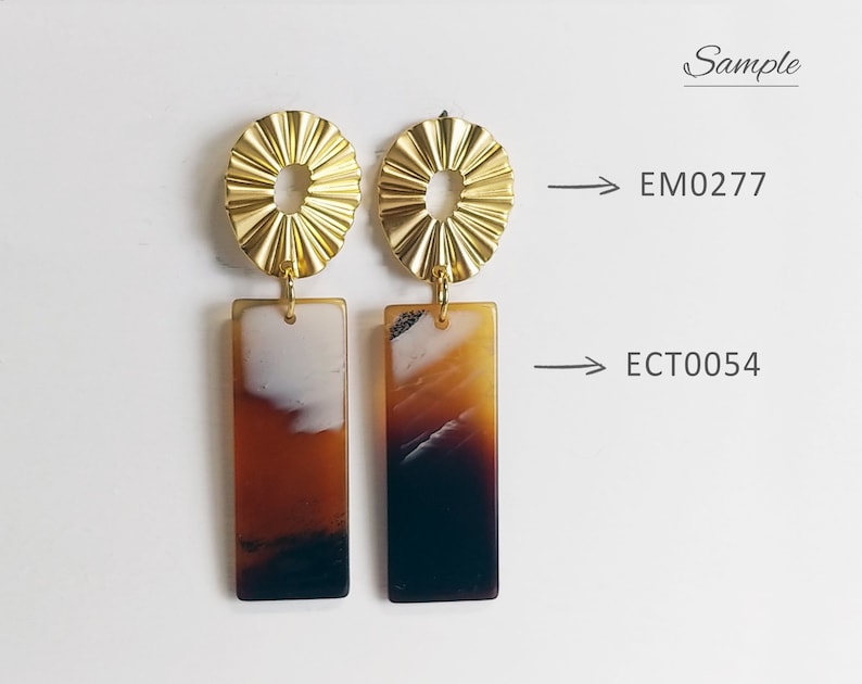 Puede incluir: Un par de pendientes de declaraci&oacute;n dorados y marrones con un dise&ntilde;o geom&eacute;trico. Los pendientes presentan una parte superior redonda de oro texturizado y una parte inferior rectangular marr&oacute;n con un patr&oacute;n de m&aacute;rmol blanco y marr&oacute;n. Los pendientes est&aacute;n etiquetados como EM0277 y ECT0054.