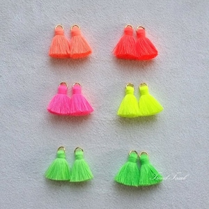 Puede incluir: Seis pares de borlas de color neón con anillos dorados. Las borlas son de tres colores: rosa, naranja y verde.