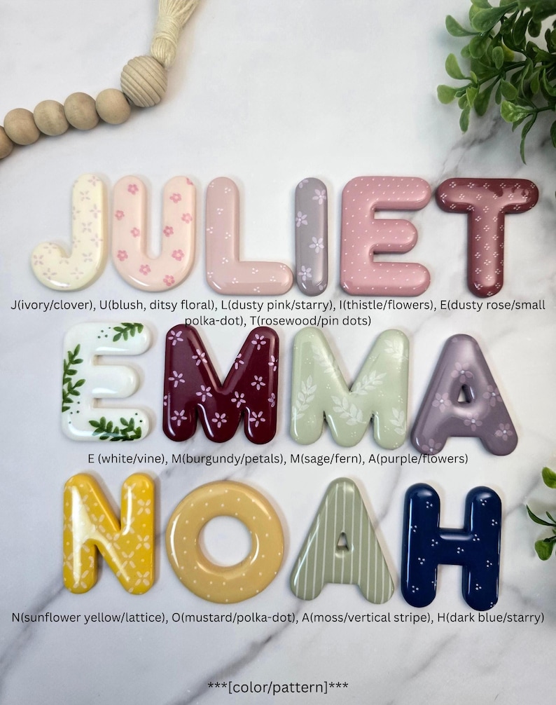May include: A collection of three-dimensional letters spelling JULIET, EMMA, and NOAH. Each letter features a unique colour and pattern, including floral, polka-dot, vine, lattice, and striped designs in shades of ivory, pink, purple, green, yellow, and blue.