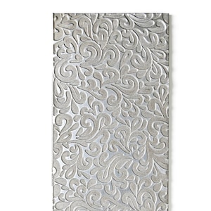 May include: A rectangular silver metal sheet featuring a raised, embossed pattern of continuous swirling paisley-like shapes. The surface has a metallic sheen with a textured finish, displaying a dense, repeating design across the entire front face.