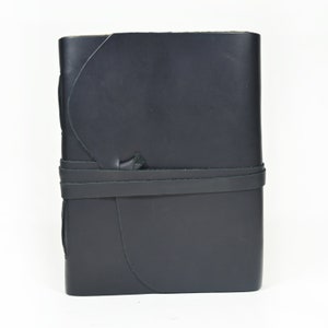 May include: A black leather-bound journal with a strap closure. The journal has a unique, curved design and is ideal for writing or sketching.
