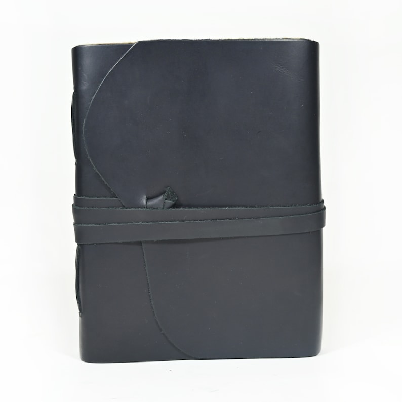 May include: A black leather-bound journal with a strap closure. The journal has a unique, curved design and is ideal for writing or sketching.