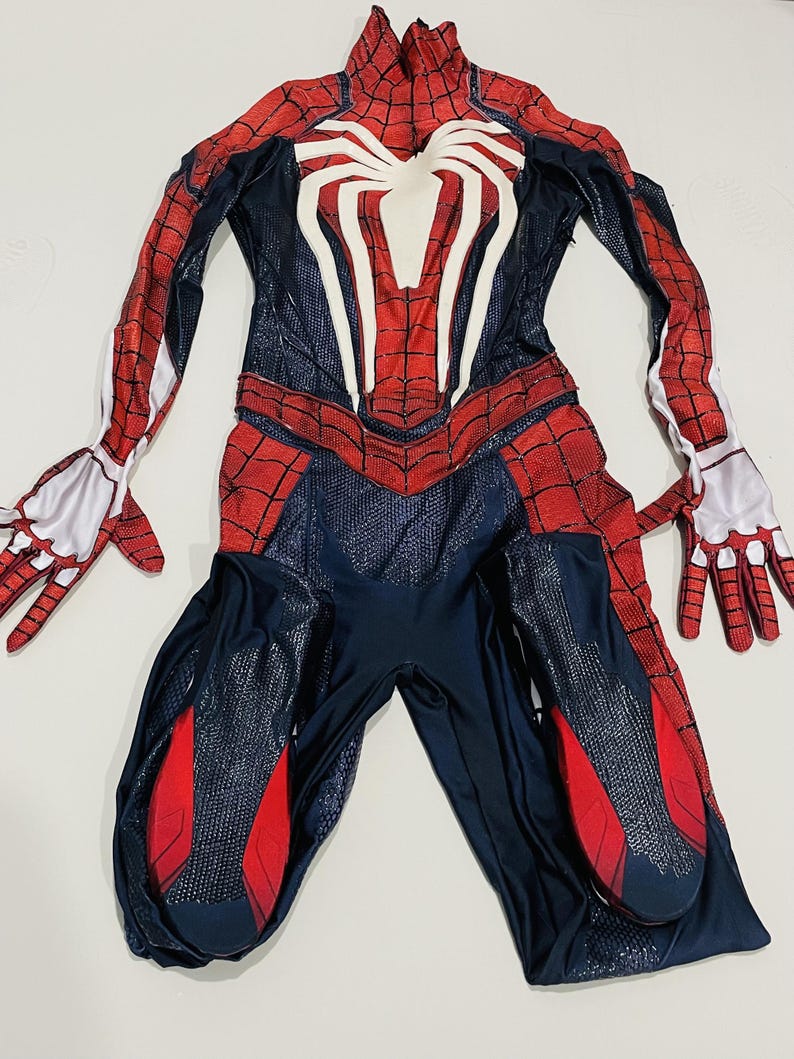 May include: A full-body Spider-Man costume in red, white, and navy blue. The costume features a large white spider emblem on the chest and red web patterns. Includes gloves and a mask.