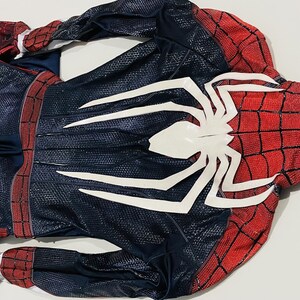 May include: A Spider-Man costume, featuring a red and black color scheme with a large white spider emblem on the chest. The costume has a textured pattern and includes gloves.
