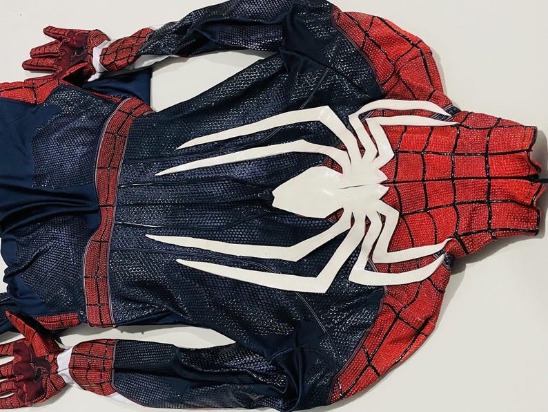 May include: A Spider-Man costume, featuring a red and black color scheme with a large white spider emblem on the chest. The costume has a textured pattern and includes gloves.