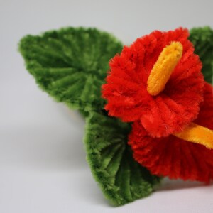 May include: A red and yellow pipe cleaner flower with green pipe cleaner leaves.