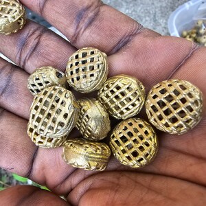 May include: A collection of gold-colored metal beads with a grid pattern. The beads are round and have a slightly textured surface.