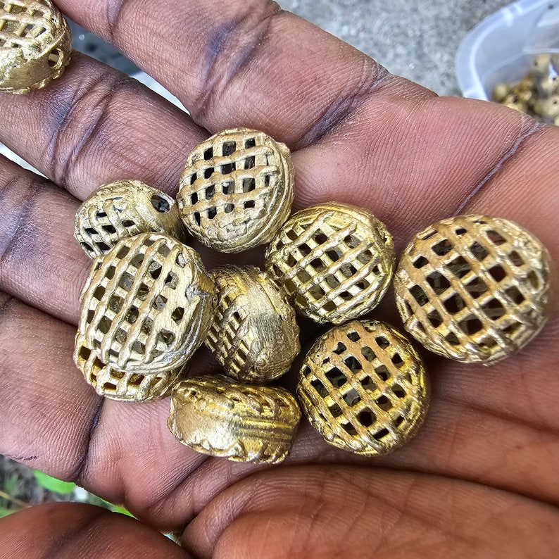 May include: A collection of gold-colored metal beads with a grid pattern. The beads are round and have a slightly textured surface.