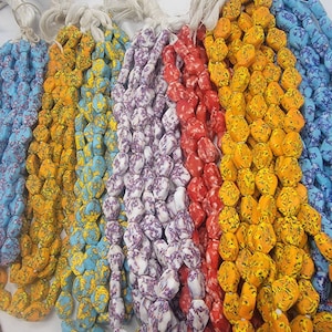 May include: Strands of colorful, textured beads in various hues, including blue, yellow, purple, and red. The beads have a unique, irregular shape and are strung together with white cord. These beads are suitable for jewelry making.