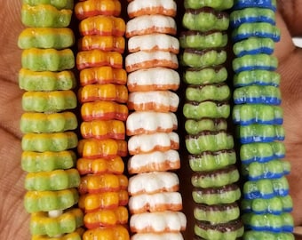 May include: Five strands of colorful star-shaped beads, each with a different color combination. The beads are green and yellow, orange and red, white and orange, green and brown, and green and blue.