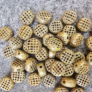 May include: A collection of gold-colored metal beads with a lattice design. The beads are round and have a slightly irregular shape.