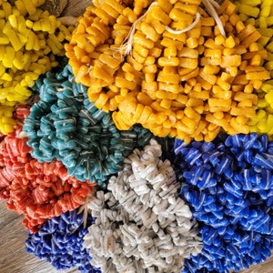 May include: A close-up of colorful glass beads arranged in a circular pattern. The beads are in shades of yellow, blue, red, and white. The beads are arranged in a circular pattern, with the yellow beads in the center and the other colors radiating outwards.