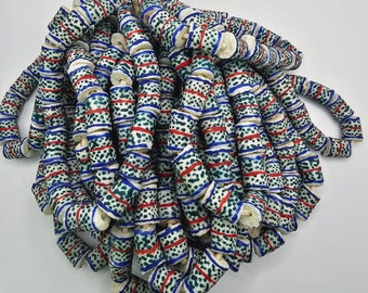 May include: A large strand of white ceramic beads with blue and red geometric patterns. The beads are strung together to form a long necklace or garland.