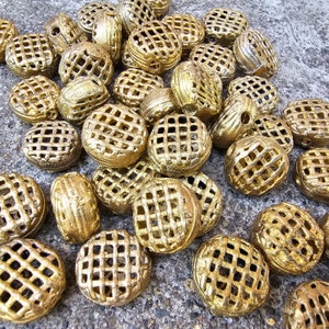 May include: A collection of gold-toned metal decorative embellishments with a lattice design. The embellishments are round and have a raised, textured surface.