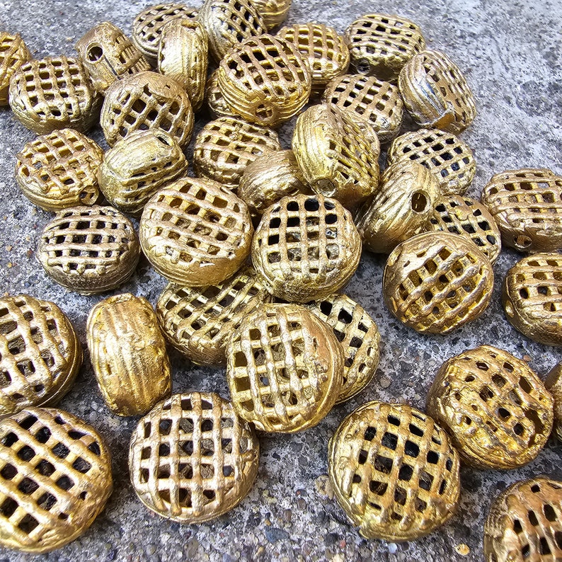 May include: A collection of gold-toned metal decorative embellishments with a lattice design. The embellishments are round and have a raised, textured surface.