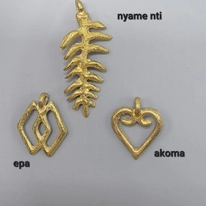 May include: Three gold-colored pendants, each with a unique design. The first pendant is a leaf-shaped design with the text "nyame ntl". The second pendant is a geometric design with the text "epa". The third pendant is a heart-shaped design with the text "akoma".