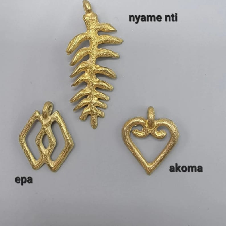 May include: Three gold-colored pendants, each with a unique design. The first pendant is a leaf-shaped design with the text "nyame ntl". The second pendant is a geometric design with the text "epa". The third pendant is a heart-shaped design with the text "akoma".