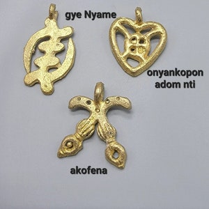 May include: Three gold-colored pendants with different designs. The first pendant is a symbol with the text "gye Nyame". The second pendant is a heart-shaped symbol with the text "onyankopon adom ntl". The third pendant is a cross-shaped symbol with the text "akofena".