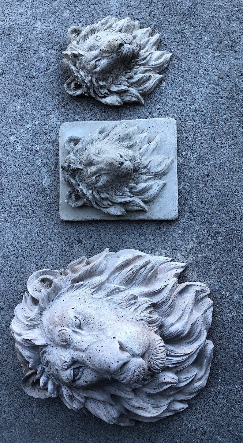 以下が含まれることがあります： グレーの石でできたライオンの頭部の彫刻が3つあり、たてがみは細かく作られています。彫刻は灰色の壁に取り付けられています。