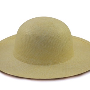 May include: A light yellow sun hat with a wide brim and a rounded crown. The hat is made of woven material, likely straw or a similar natural fiber. The brim is approximately 14 inches in diameter, providing ample shade.