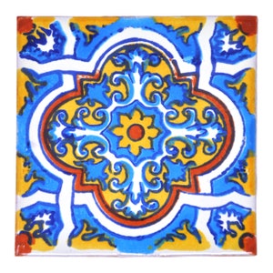 Puede incluir: Un azulejo cuadrado de cerámica con un patrón floral colorido. El azulejo presenta un motivo central de una flor amarilla con un centro rojo, rodeado de diseños azules y blancos en espiral. El azulejo está enmarcado por un borde amarillo con acentos rojos y azules.