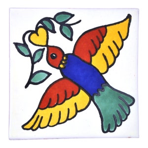 Op de afbeelding: Vierkante keramische tegel met een kleurrijk vogelontwerp. De vogel heeft rode, gele, blauwe en groene veren en houdt een tak met een gele hartvormige blad vast. De tegel is wit en glanzend.