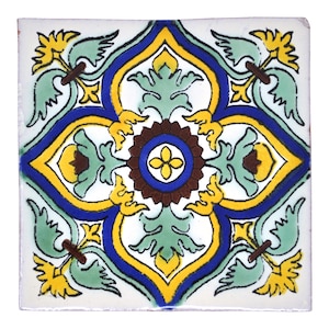 May include: A white ceramic tile featuring a blue, yellow and green floral design. The tile has a central motif of a brown circle with a blue ring and a yellow flower in the centre.