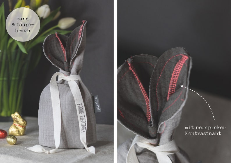 Puede incluir: Una bolsa de regalo de tela gris con una cinta blanca y el texto "Frohe Ostern!" en negro. La bolsa tiene forma de tulip&aacute;n con un detalle de costura rosa.