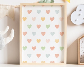 Puede incluir: Decoración de habitación infantil con una impresión enmarcada con un patrón de corazones pastel, un rinoceronte de peluche gris, una luz nocturna en forma de nube blanca y un estante de madera con un patrón de estrellas y una taza de cerámica blanca con una cara de oso.