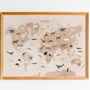 May include: A beige world map with a brown wooden frame. The map features various animals from different continents, including a polar bear, a giraffe, a kangaroo, and a penguin. The text "Our World" is printed at the top of the map.