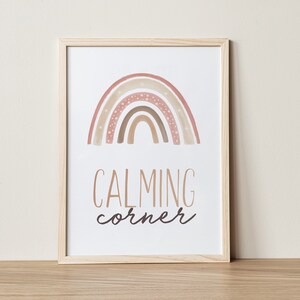 Puede incluir: Una impresi&oacute;n enmarcada con un arco&iacute;ris de acuarela en tonos rosa, marr&oacute;n y beige con estrellas blancas. El texto "CALMING corner" est&aacute; escrito debajo del arco&iacute;ris.