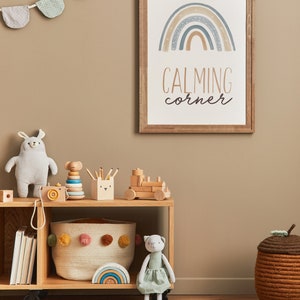 May include: A wooden shelf with a variety of toys, including a stuffed animal, a wooden train, and a rainbow-colored stacking toy. The shelf is decorated with a framed print that says "Calming Corner" and a rainbow with stars.