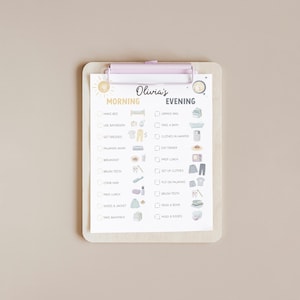 May include: A light-colored clipboard with a checklist for morning and evening routines. The checklist includes tasks like "Make Bed" and "Brush Teeth." The name "Olivia's" is written at the top. The clipboard has a light purple clip.
