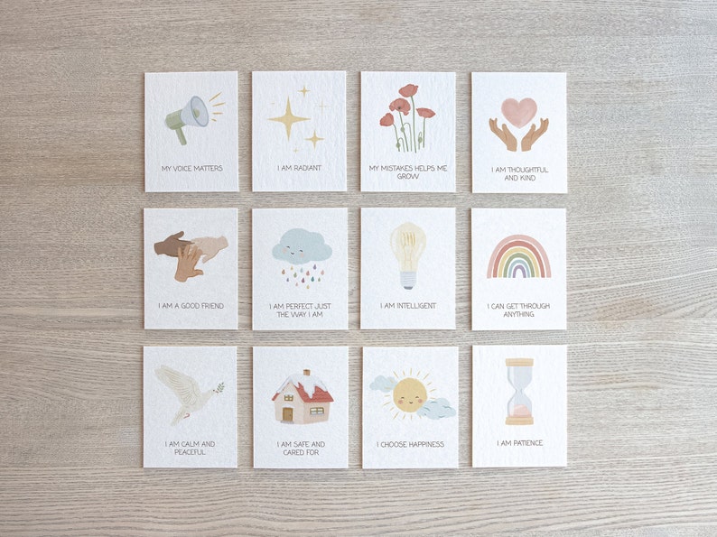 May include: Set of 12 affirmation cards with colorful illustrations and positive messages. The cards feature images of a megaphone, a star, flowers, hands holding a heart, hands shaking, a cloud with raindrops, a lightbulb, a rainbow, a dove, a house, a sun, and an hourglass. The text on the cards includes phrases like "My voice matters", "I am radiant", "My mistakes help me grow", "I am thoughtful and kind", "I am a good friend", "I am perfect just the way I am", "I am intelligent", "I can get through anything", "I am calm and peaceful", "I am safe and cared for", "I choose happiness", and "I am patience".
