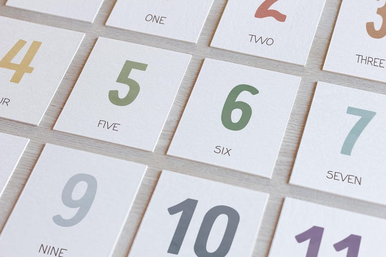May include: A set of ten cards with numbers one through ten written on them. Each card has a different color number. The numbers are written in a playful, rounded font.