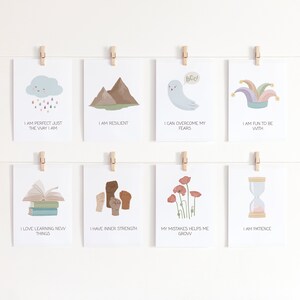 May include: Eight printable affirmation cards with colorful illustrations and positive messages. The cards feature a cloud with raindrops, mountains, a ghost, a jester's hat, a stack of books, a fist, a poppy flower, and an hourglass.