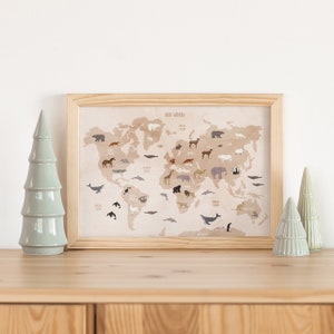 May include: A framed world map with a beige background and illustrations of animals from different continents. The map is titled "Our World" and is surrounded by a light wood frame.