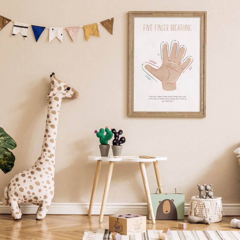 May include: A framed illustration of a hand with five fingers, labeled "Five Finger Breathing". The illustration shows how to breathe in and out using each finger. The illustration is in a light brown frame and is hanging on a light beige wall.