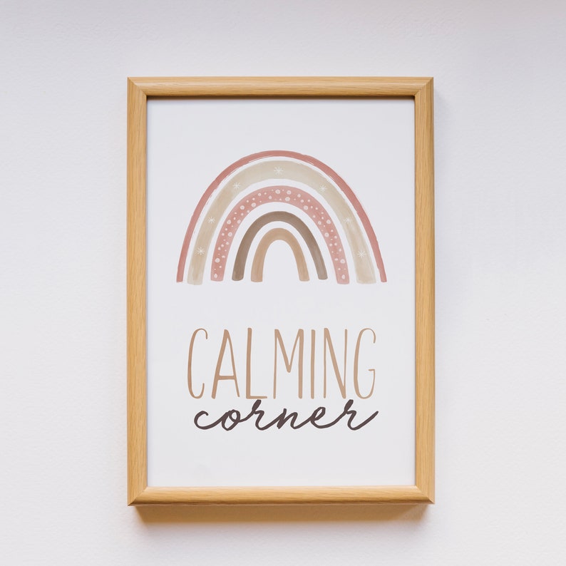 Puede incluir: Una impresi&oacute;n enmarcada con un arco&iacute;ris de acuarela en tonos rosa, marr&oacute;n y blanco sobre un fondo blanco. El texto "CALMING corner" est&aacute; impreso debajo del arco&iacute;ris.