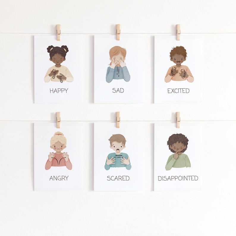 May include: Six white cards with illustrations of children expressing different emotions: happy, sad, excited, angry, scared, and disappointed. Each card is held by a wooden clothespin on a white string. The word for each emotion is printed below the illustration.