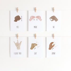 May include: Six white cards with black text and illustrations of hands signing different words in American Sign Language. The words are "YES", "MORE", "NO", "I LOVE YOU", "EAT", and "DRINK".
