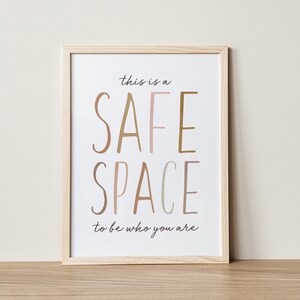 May include: A framed print with the text "This is a safe space to be who you are." The words "safe" and "space" are in large, colorful letters.