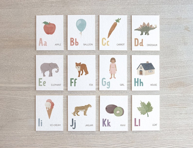 May include: A set of 12 alphabet flash cards featuring colorful illustrations of objects and animals. Each card has a letter, the letter name, and the word for the image. The letters are in uppercase and lowercase. The images are in a cartoon style. The cards are printed on white cardstock.